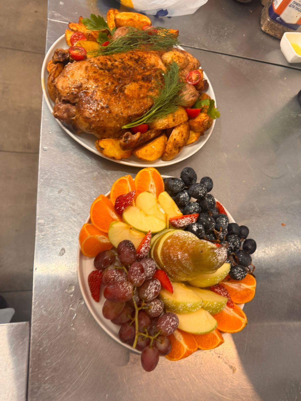 Запечённая птица с картофелем и фруктовая тарелка на банкетном столе